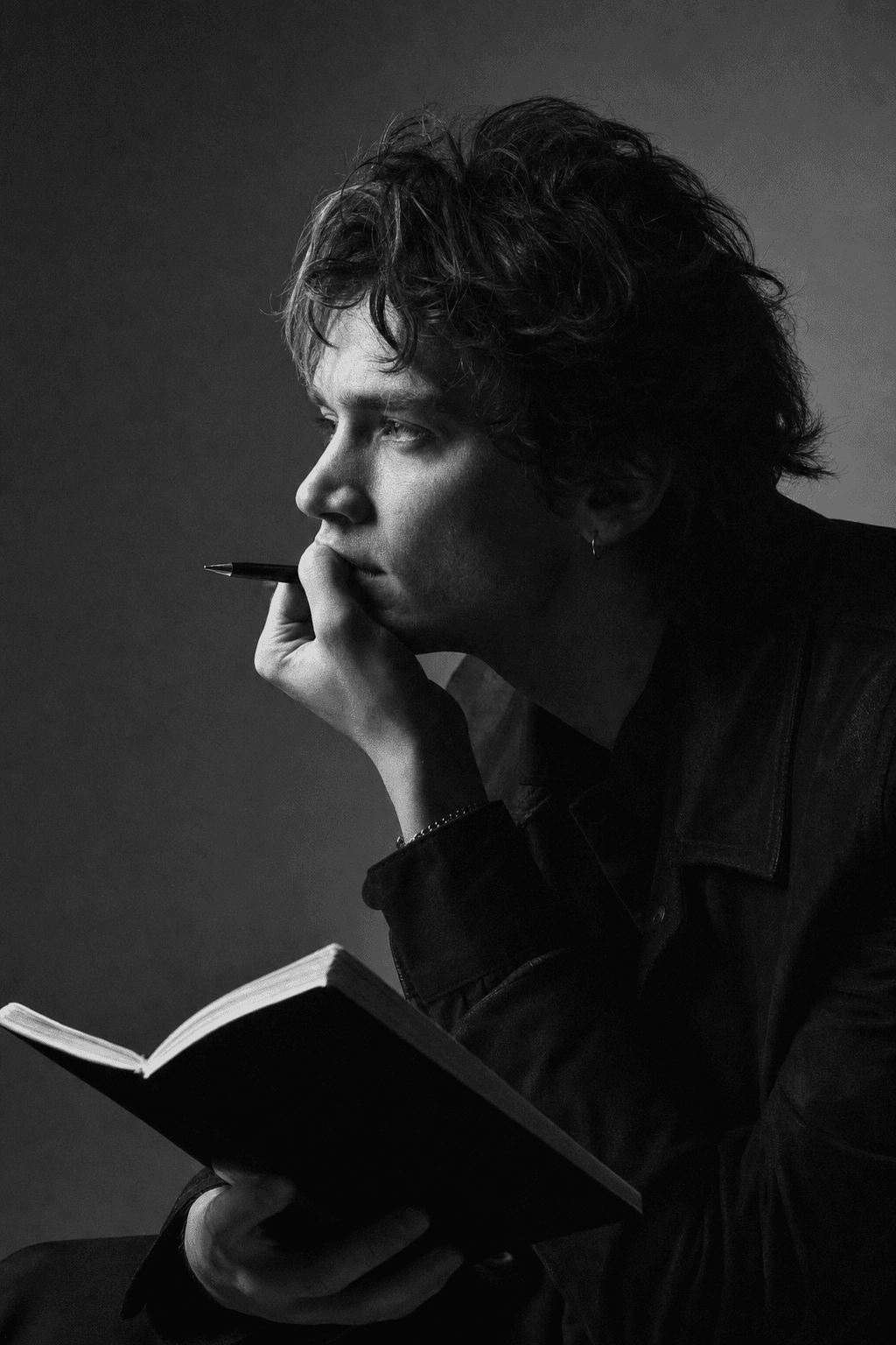 Editorial black and white portrait of a person in profile, mid-thought, with a notebook