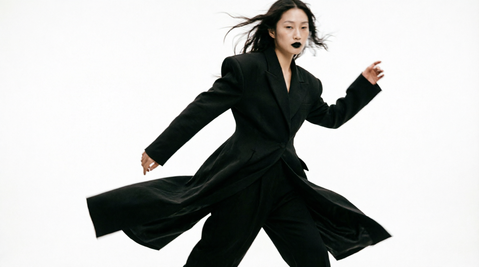 Nº9 Atelier campaign image, model in a flowing black look mid-stride